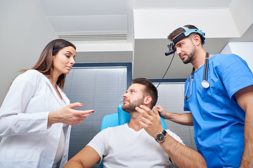 Obraz premium A doctor and his assistant consulting with the patient in the hospital room.
