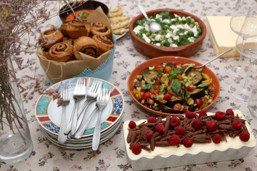 Chicken with roasted pepper sauce, roasted aubergine, feta cheese salad, tapenade bread rolls and tiramisu served on a table. Selective focus.