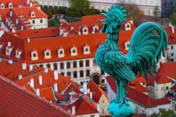 Fototapeta premium Weathercock on the roof, Czech, Prague, city view. Prague architecture, red roofs, weather vane shape of rooster.