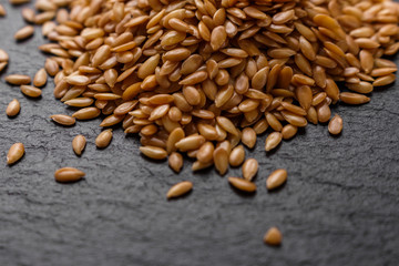 seeds of golden flax on a dark stone background