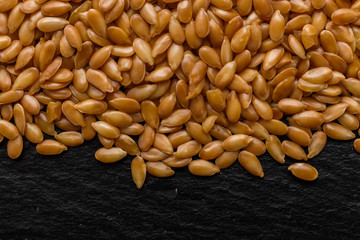 seeds of golden flax on a dark stone background
