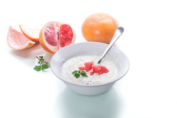 sweet oatmeal with slices of red grapefruit in a ceramic bowl
