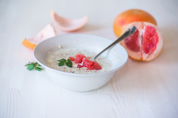 sweet oatmeal with slices of red grapefruit in a ceramic bowl