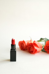 Obraz na płótnie Canvas Beauty cosmetic white background with red lipstick and roses. Decorative composition with cosmetics and flowers. Makeup essentials, Cosmetic products. Feminine Modern fashion mockup, copy space.