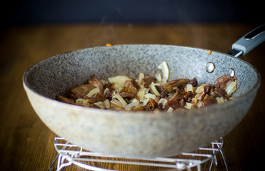 organic forest mushrooms fried with onions in a pan