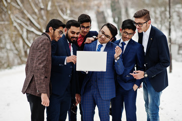 Group of six indian businessman in suits posed outdoor in winter day at Europe, looking on laptop.