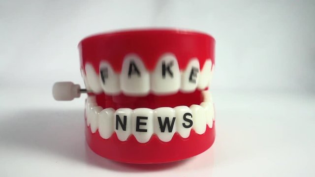 Fake News gossip and chatter. Comical toy chattering teeth in slow motion marked with fake news on the teeth.