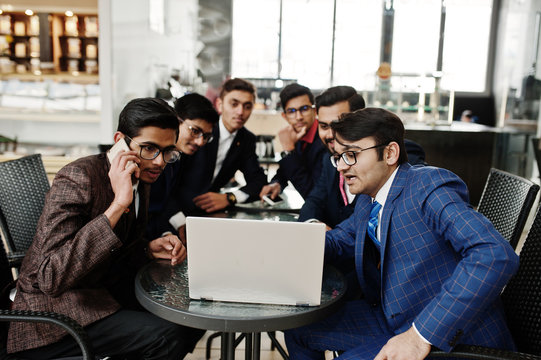 Group of six indian business man in suits sitting at office on cafe and looking at laptop.