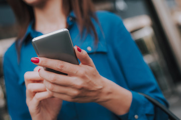 Concept of success and well-being. Close up portrait of stylish business lady holding mobile phone in hands