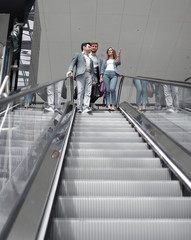 businesspeople moving down on escalator in office