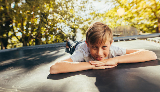Little boy resting on trampoline after playing - Powered by Adobe