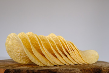 Bunch of salty crisps presented on a wooden board, grey background