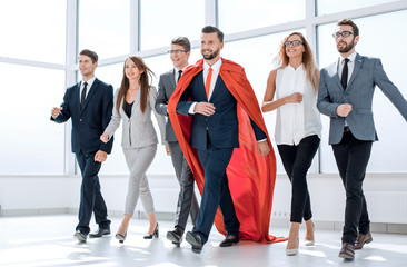 businessman in a red cloak marching with the business team