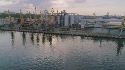 Odessa industrial seaport with giant cranes and huge metallic tanks in summer
