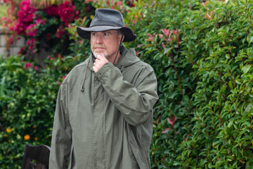 Portrait of senior man in park thinking during rain storm