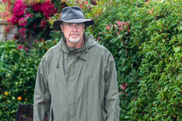 Portrait of senior man in park during rain storm