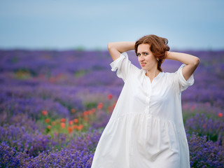 Fototapeta na wymiar Young girl in white dress, posing in a lavender field.