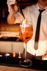 Making Aperol cocktail in wine glass. With ice and orange.