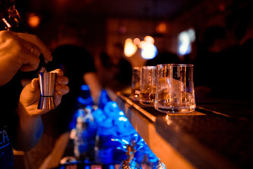 The barman pours alcohol into a glass. Close-up.