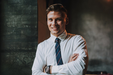 Concept of success and confidence. Waist up portrait of handsome smiling businessman crossing hands on chest and looking on camera