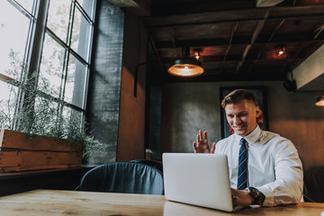 Concept of free communication. Waist up portrait of handsome smiling businessman having video chat...