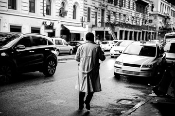 a man wearing a gabardine crossing the street