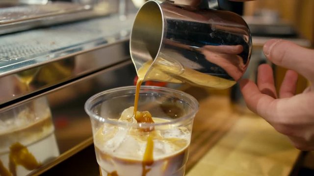Barista is Pouring Coffee to Takeaway Cup Making Ice Cream Latte using Professional Machine in the Cafe