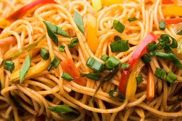 Schezwan Noodles or vegetable Hakka Noodles or chow mein is a popular Indo-Chinese recipes, served in a bowl or plate with wooden chopsticks. selective focus