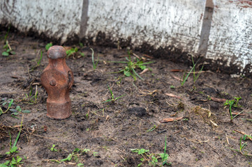 An old forsaken ball peen hammer head stands on end in the dirt with bokeh backgound.