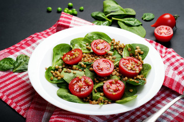Salad of baby spinach leaves, green lentils, cherry tomatoes, olive oil and lemon juice in a bowl...