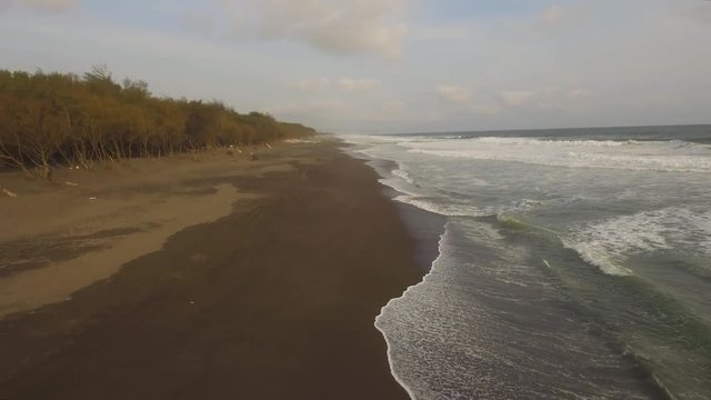 aerial view sandy beach near ocean with big waves at sunset time in tropical resort, Yogyakarta, Indonesia. seascape, ocean and beautiful beach. Travel concept. Indonesia, java
