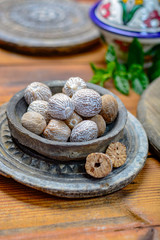 Old clay bowl with whole nutmegs close up, spices collection