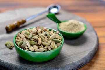 Bowl with cardamom pots and cardamom powder, used for cooking and traditional medicine close up, spices collection