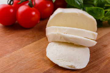 Mozzarella tomatoes and basil on a wooden rustic background