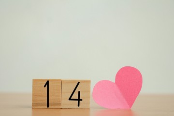 number 14 on wooden cubes with pink heart shaped paper love and valentine's day concept. 