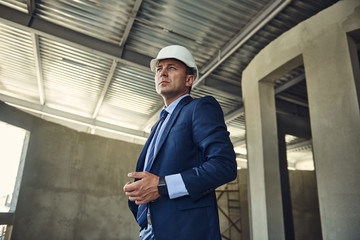 Waist up portrait of architect in helmet is locating on construction site. Copy space on left side
