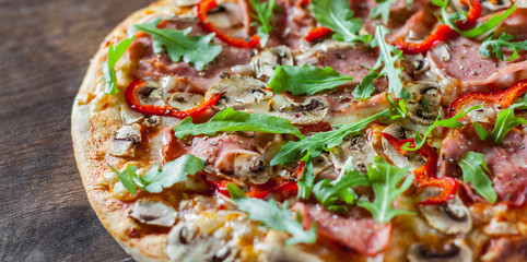 Pizza with Mozzarella cheese, mushrooms, ham, tomato sauce, salami, pepper, Spices and Fresh arugula. Italian pizza on wooden table background