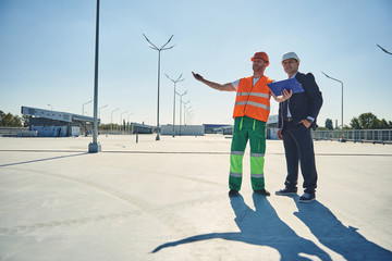 Full length of young engineer is showing to project manager construction site. Copy space on left...