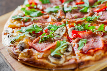 Pizza with Mozzarella cheese, mushrooms, ham, tomato sauce, salami, pepper, Spices and Fresh arugula. Italian pizza on wooden table background