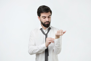 Spanish man in white shirt dressing up and adjusting tie. Studio shoot
