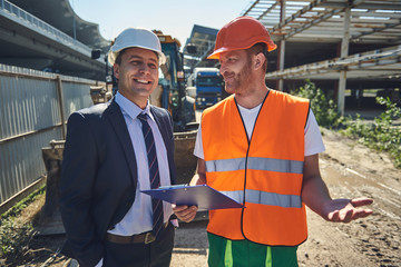 Architect and worker are standing at construction site