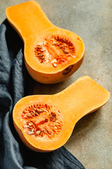 View on raw halves of butternut squash on a kitchen table. Seasonal vegetable food, still life.