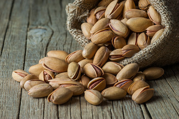 Pistachio in nutshell in burlap sack or sackcloth on wooden rustic backdrop, composition of pistachios great for healthy and dietary nutrition. Concept of nuts
