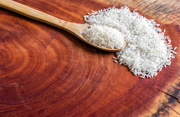 white rice in wooden spoon and spread over rustic wooden board