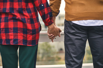 Cropped photo of young couple is locating outdoor while holding hands together