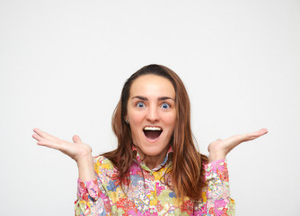 Surprised young woman straightens her arms to the side, stands on a white background. Looking at camera