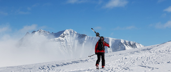 Naklejka na ściany i meble Skier with skis go up to top of mountain