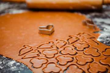 Baking for Christmas with dark dough, roll, spices and cookie cutters. Recipe for making ginger biscuits. Cookies prepared for baking in the oven - Raw cookies on table covered with flour for baking.