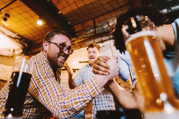 Friends having arm wrestling in pub.