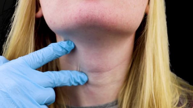 Palpation of the thyroid gland and throat. Examination by a doctor. Black background
